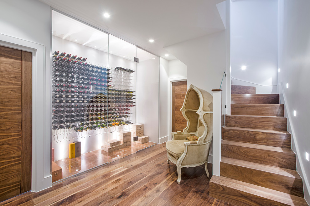 Contemporary wine cellar in London with medium hardwood floors, storage racks and brown floor.