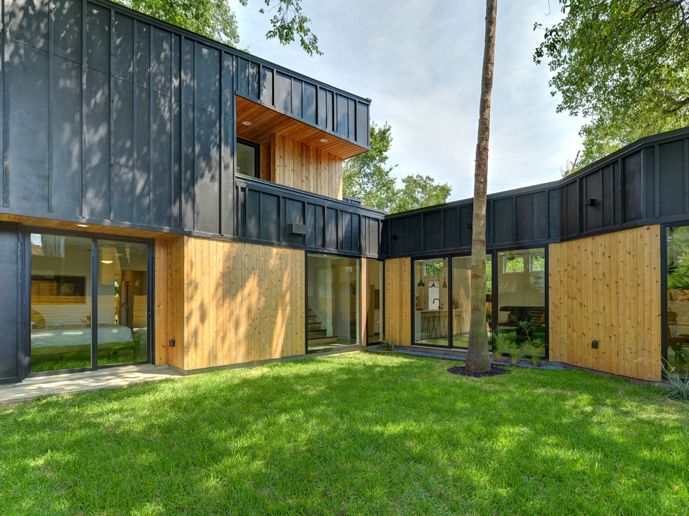 Réalisation d'une façade de maison noire tradition en bois à un étage avec un toit en appentis.