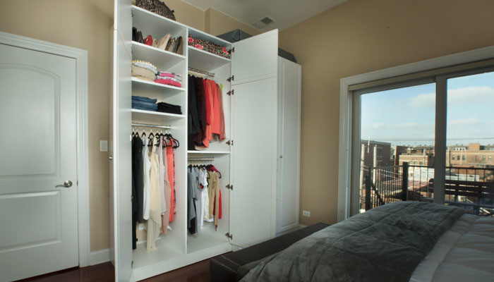 Mid-sized transitional women's built-in wardrobe in Chicago with raised-panel cabinets, white cabinets and dark hardwood floors.