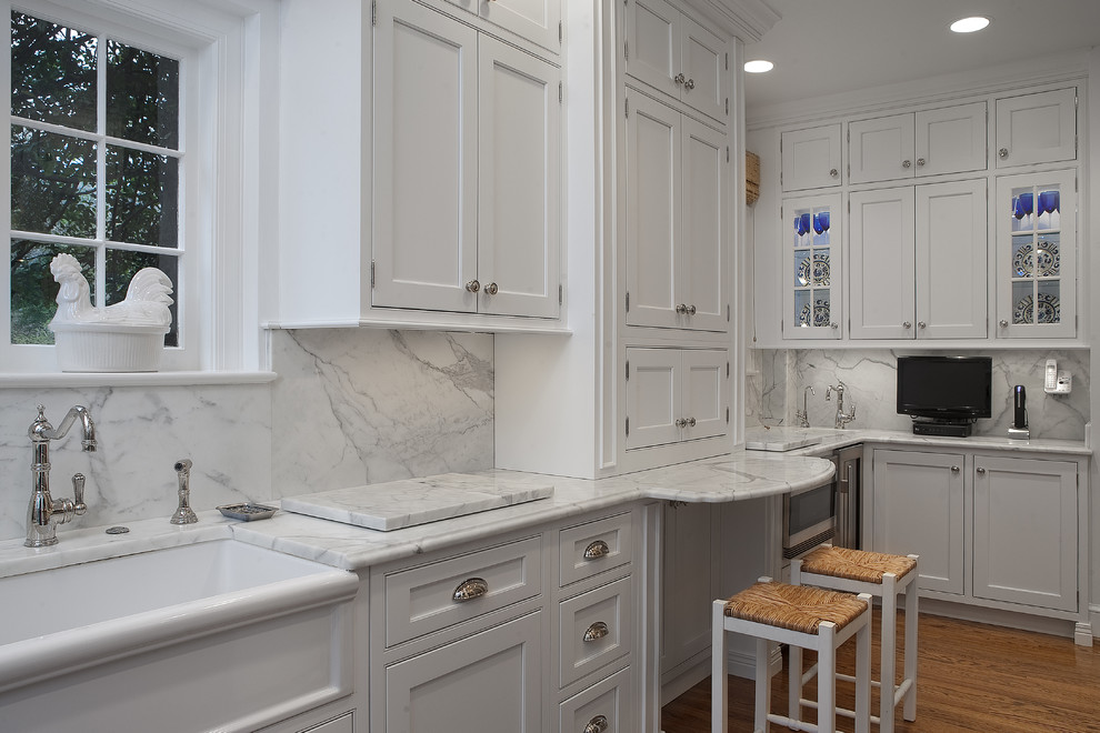 Design ideas for a traditional galley separate kitchen in DC Metro with a farmhouse sink, beaded inset cabinets, white cabinets, white splashback, marble benchtops, stainless steel appliances, light hardwood floors and marble splashback.