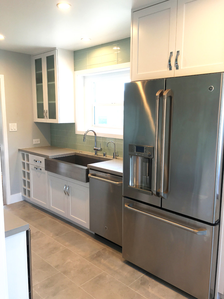 This is an example of a mid-sized transitional galley eat-in kitchen in Los Angeles with a farmhouse sink, shaker cabinets, white cabinets, quartz benchtops, blue splashback, glass tile splashback, stainless steel appliances and porcelain floors.