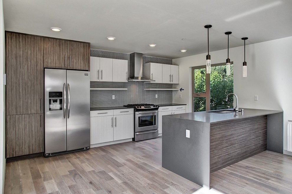 Mid-sized contemporary single-wall open plan kitchen in Seattle with an undermount sink, flat-panel cabinets, distressed cabinets, quartz benchtops, glass tile splashback, stainless steel appliances and with island.