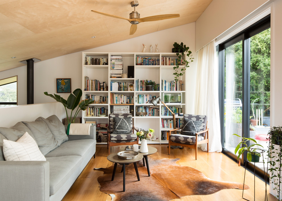 This is an example of a contemporary open concept living room in Auckland with white walls, medium hardwood floors and brown floor.