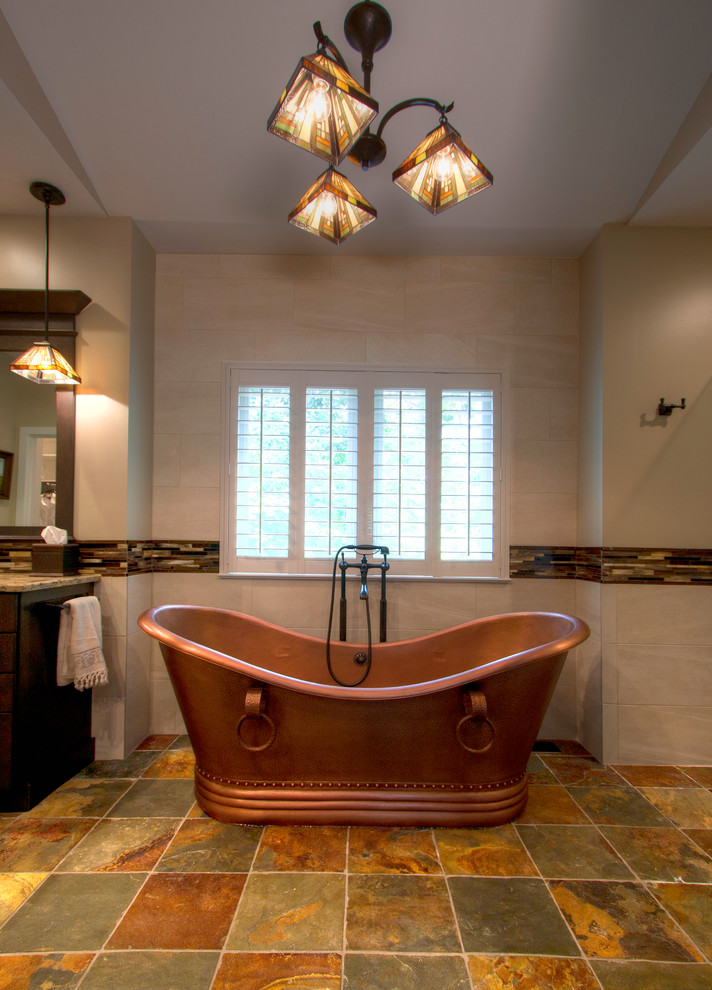This is an example of a mid-sized arts and crafts master bathroom in St Louis with shaker cabinets, dark wood cabinets, a freestanding tub, a two-piece toilet, multi-coloured tile, stone tile, beige walls, an undermount sink and engineered quartz benchtops.