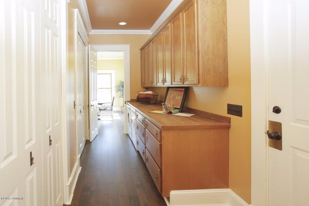 Large traditional galley utility room in Grand Rapids with flat-panel cabinets, medium wood cabinets, wood benchtops, dark hardwood floors, a side-by-side washer and dryer and orange walls.