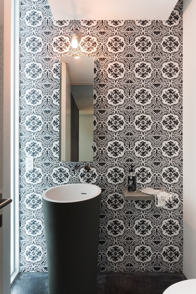 Inspiration for a small contemporary powder room in Miami with a pedestal sink, multi-coloured walls, concrete benchtops, black tile, ceramic tile, concrete floors, a one-piece toilet and black floor.