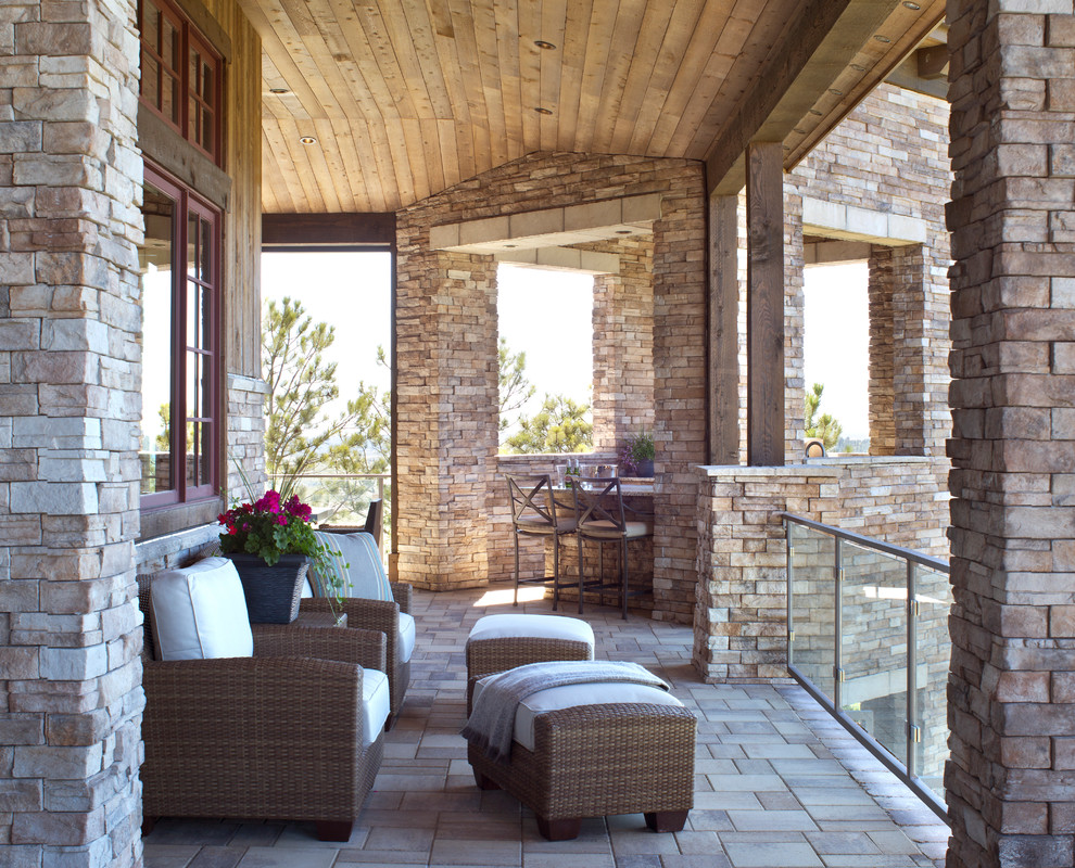 Inspiration for a country deck in Denver with a roof extension and glass railing.