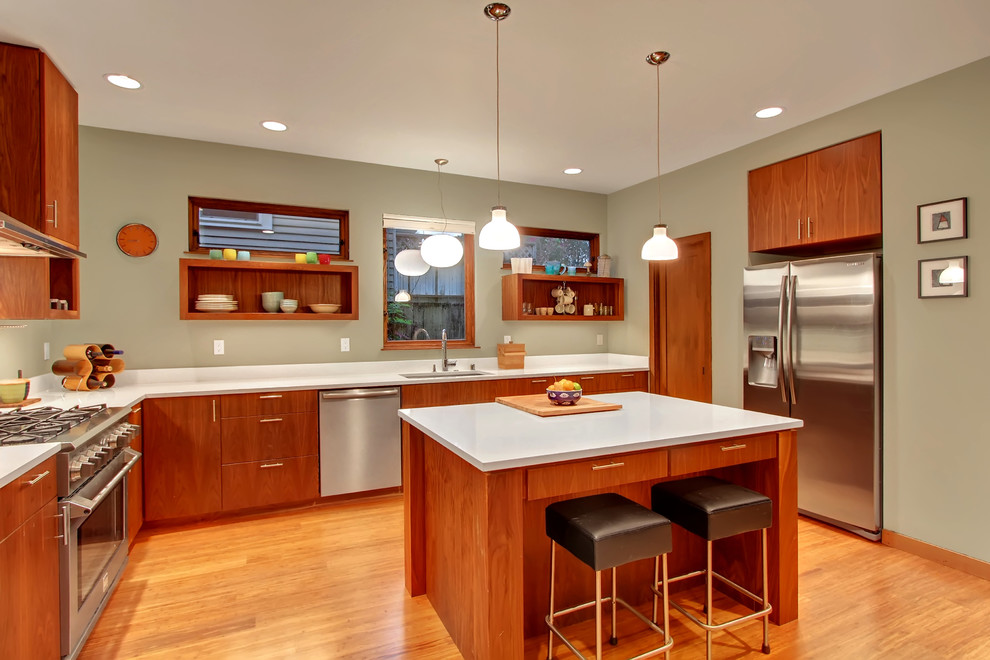 Design ideas for a contemporary u-shaped kitchen in Seattle with flat-panel cabinets, medium wood cabinets, quartz benchtops, white splashback, stainless steel appliances, medium hardwood floors, with island and white benchtop.