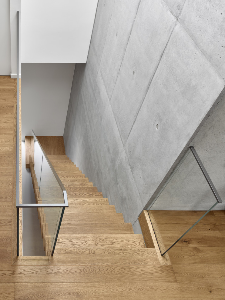Mid-sized minimalist wooden straight glass railing staircase photo in Berlin with wooden risers