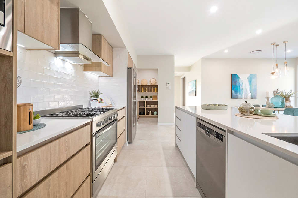 This is an example of a beach style galley kitchen pantry in Brisbane with a double-bowl sink, white splashback, ceramic splashback, stainless steel appliances, ceramic floors, with island and beige floor.