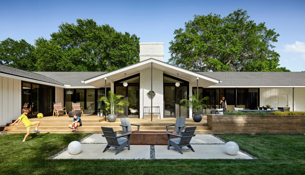 Immagine di un grande patio o portico minimalista dietro casa con pedane, un tetto a sbalzo e scale