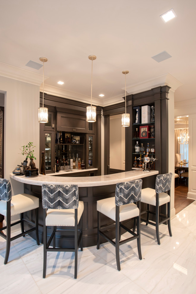 Inspiration for a small transitional u-shaped seated home bar in New York with glass-front cabinets, dark wood cabinets, marble benchtops, white benchtop, an undermount sink, marble floors and white floor.