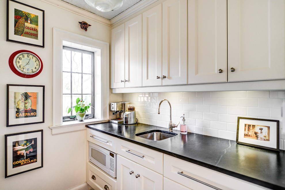 Photo of a traditional kitchen in Toronto with recessed-panel cabinets, subway tile splashback, white appliances, white cabinets, soapstone benchtops and white splashback.