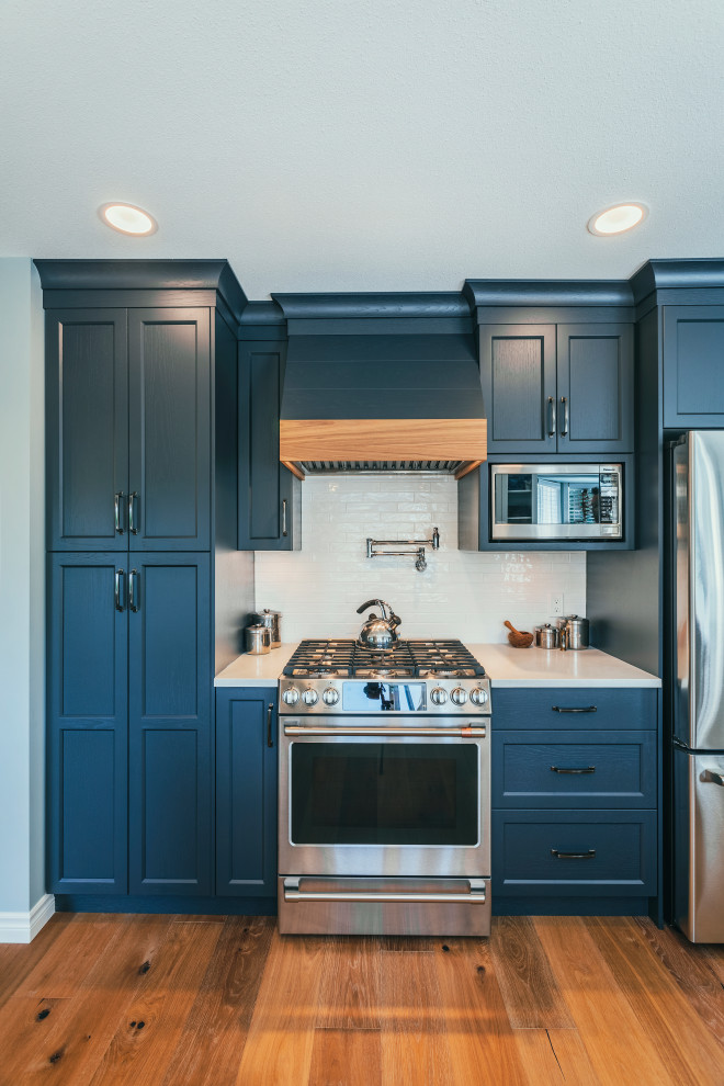 Large minimalist galley light wood floor and brown floor open concept kitchen photo in Vancouver with an undermount sink, shaker cabinets, white cabinets, quartz countertops, white backsplash, subway tile backsplash, stainless steel appliances and white countertops