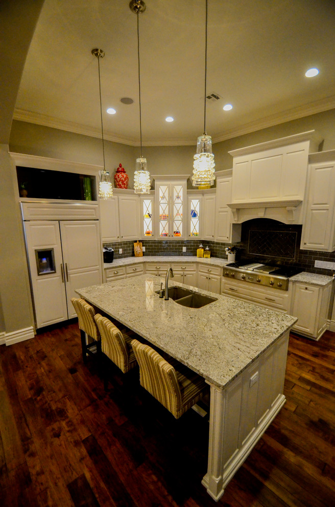 Large transitional u-shaped dark wood floor open concept kitchen photo with a double-bowl sink, raised-panel cabinets, white cabinets, granite countertops, gray backsplash, stainless steel appliances and an island