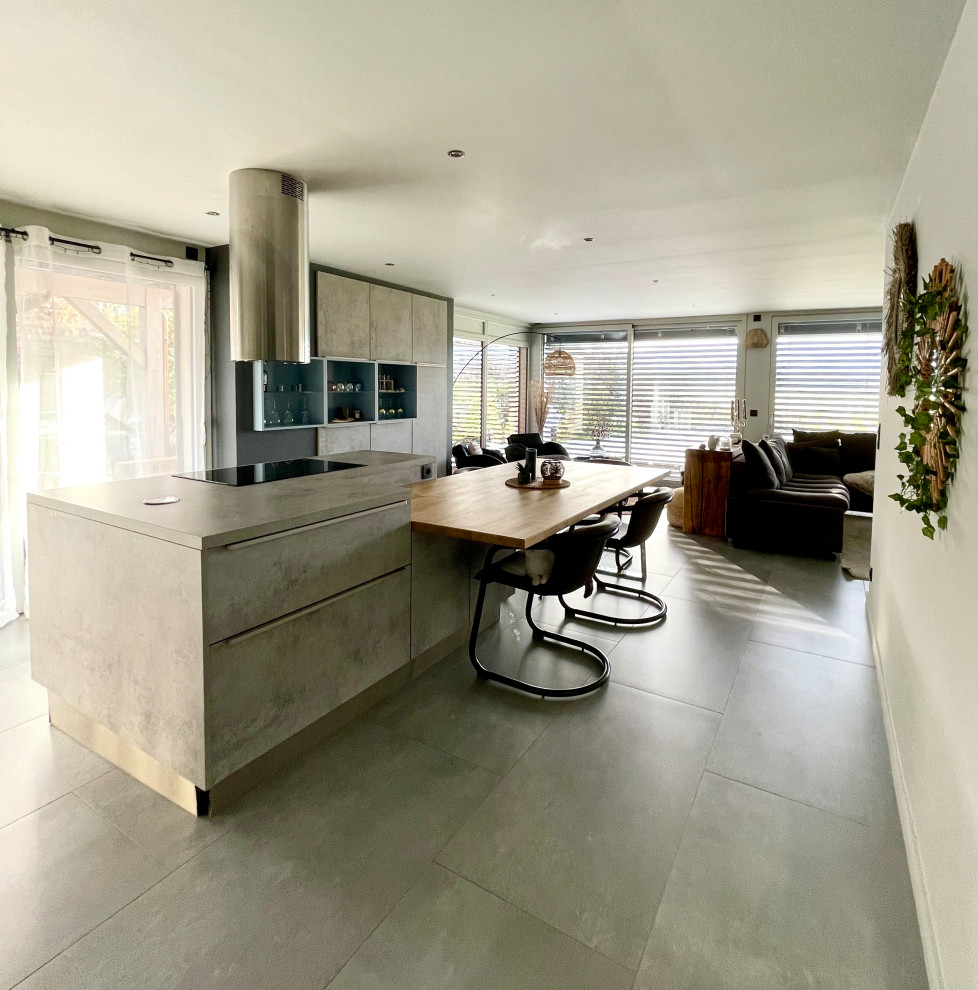 Inspiration for a large contemporary l-shaped kitchen/diner in Lyon with ceramic flooring, grey floors, a submerged sink, flat-panel cabinets, grey cabinets, concrete worktops, black appliances, an island and grey worktops.