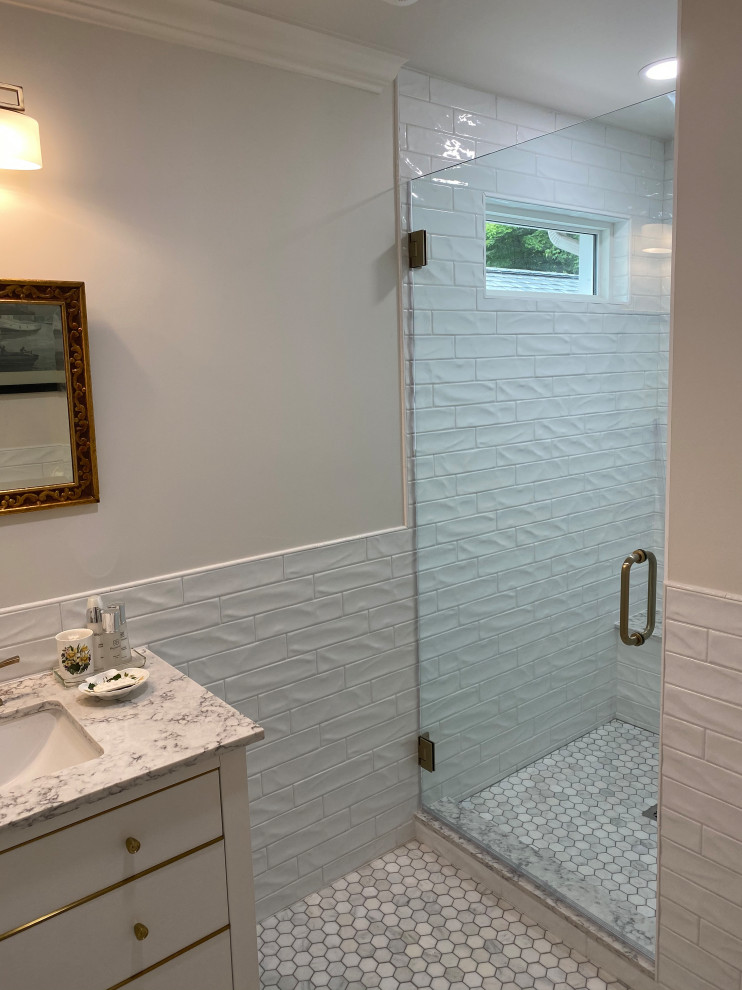 This is an example of a mid-sized traditional 3/4 bathroom in Cincinnati with furniture-like cabinets, white cabinets, an open shower, a two-piece toilet, white tile, subway tile, white walls, marble floors, an undermount sink, engineered quartz benchtops, multi-coloured floor, a hinged shower door, white benchtops, a shower seat, a single vanity, a freestanding vanity and decorative wall panelling.
