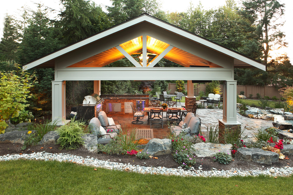 Large traditional backyard patio in Seattle with natural stone pavers, a gazebo/cabana and an outdoor kitchen.