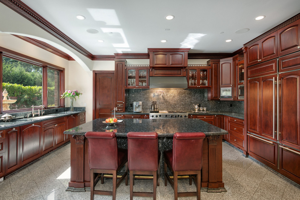 This is an example of an expansive u-shaped eat-in kitchen in Seattle with an undermount sink, raised-panel cabinets, dark wood cabinets, granite benchtops, black splashback, granite splashback, panelled appliances, marble floors, with island, multi-coloured floor, black benchtop and recessed.