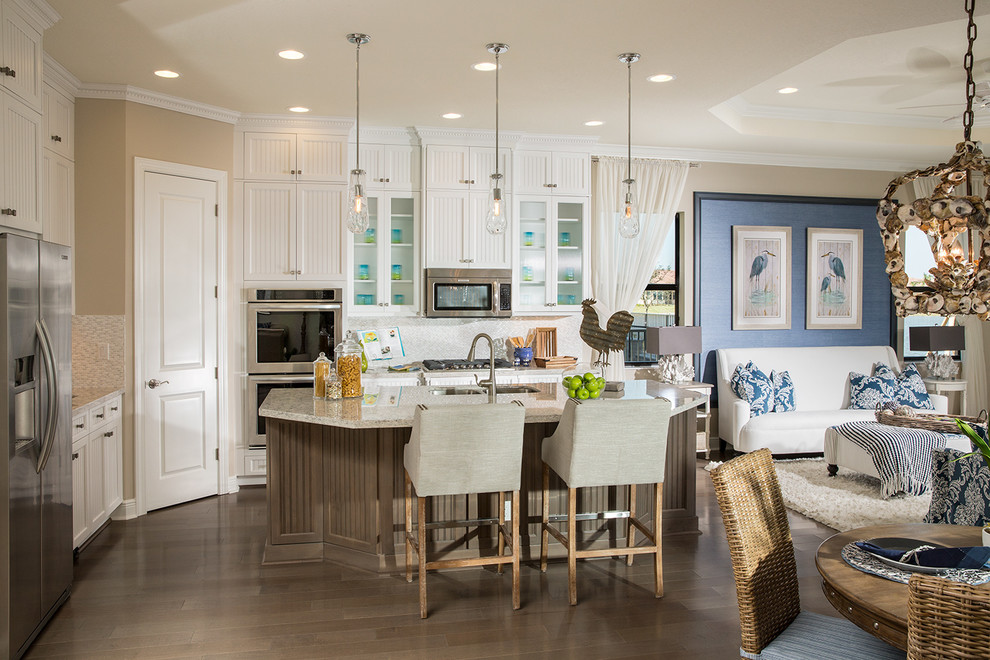 Mid-sized beach style l-shaped dark wood floor and brown floor open concept kitchen photo in Miami with recessed-panel cabinets, white cabinets, white backsplash, mosaic tile backsplash, stainless steel appliances, an island, an undermount sink and granite countertops