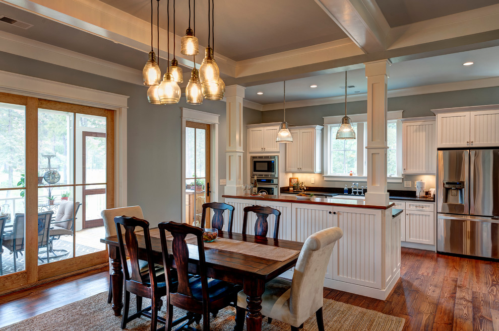 This is an example of a mid-sized country single-wall eat-in kitchen in Charleston with medium hardwood floors, a farmhouse sink, louvered cabinets, white cabinets, wood benchtops, stainless steel appliances and with island.