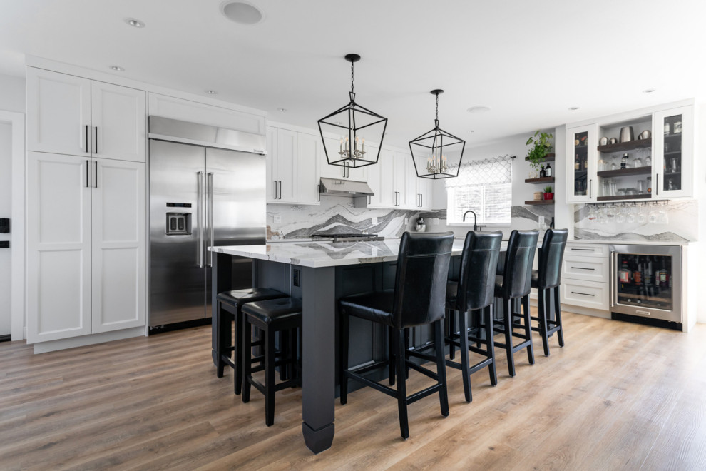 Example of a mid-sized transitional u-shaped medium tone wood floor and brown floor eat-in kitchen design with an undermount sink, recessed-panel cabinets, white cabinets, quartz countertops, white backsplash, stone slab backsplash, stainless steel appliances, an island and white countertops