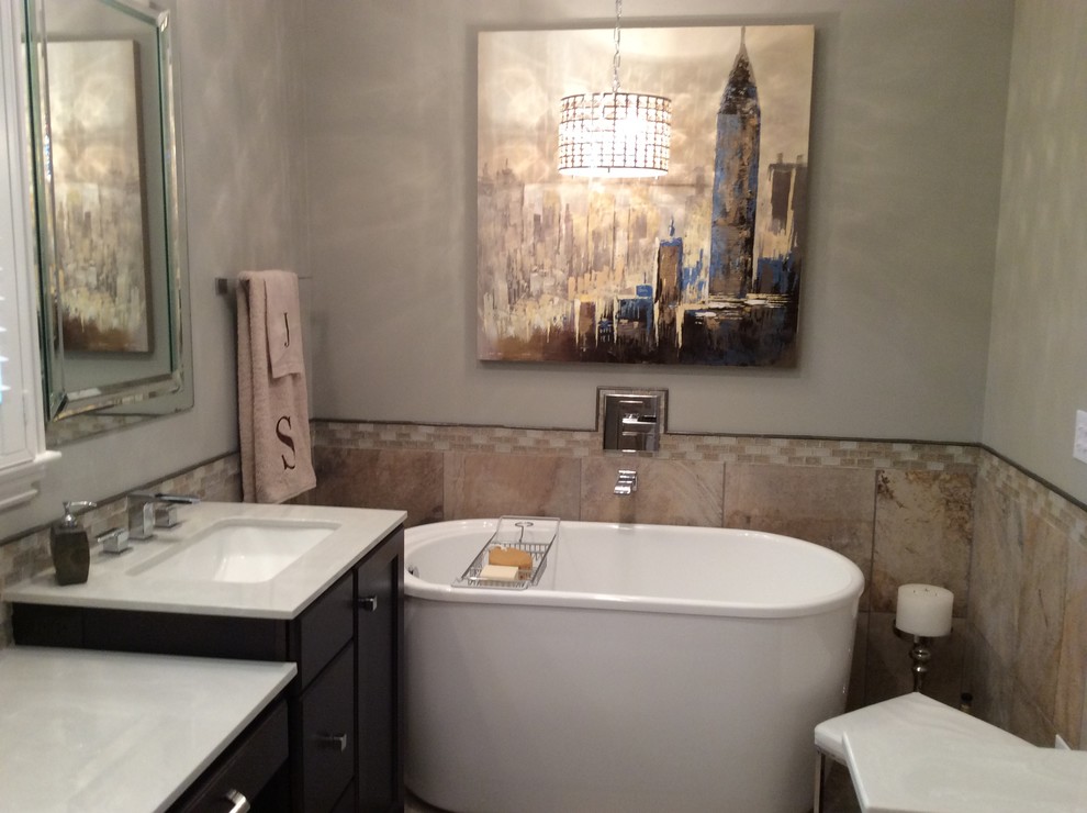 Example of a mid-sized transitional master beige tile and ceramic tile ceramic tile freestanding bathtub design in Birmingham with an undermount sink, flat-panel cabinets, dark wood cabinets, marble countertops, a two-piece toilet and beige walls