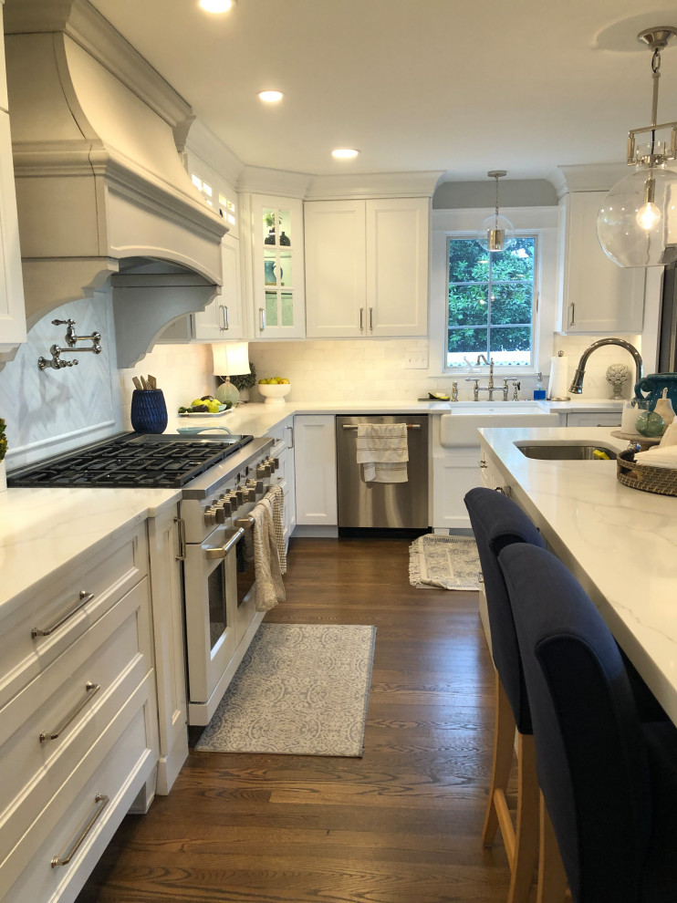 Eat-in kitchen - large transitional l-shaped medium tone wood floor and brown floor eat-in kitchen idea in Baltimore with a farmhouse sink, flat-panel cabinets, white cabinets, quartz countertops, white backsplash, subway tile backsplash, stainless steel appliances, an island and white countertops