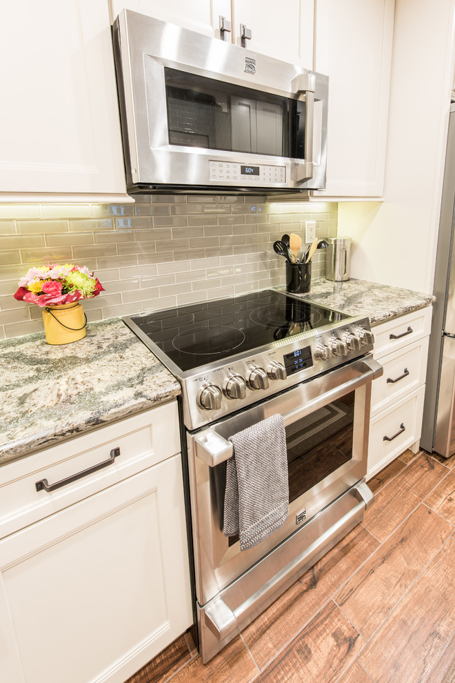 Mid-sized transitional galley eat-in kitchen photo with an undermount sink, white cabinets, quartz countertops, gray backsplash, glass tile backsplash, stainless steel appliances, no island and shaker cabinets