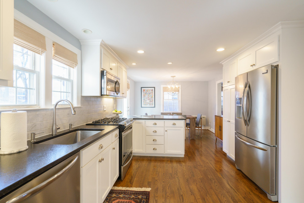 Eat-in kitchen - small transitional u-shaped medium tone wood floor and brown floor eat-in kitchen idea with an undermount sink, shaker cabinets, white cabinets, granite countertops, white backsplash, marble backsplash, stainless steel appliances, a peninsula and black countertops