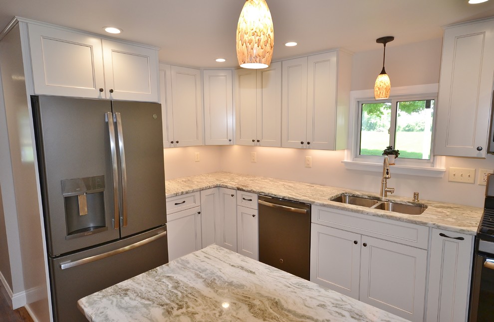Photo of a large transitional l-shaped eat-in kitchen in Philadelphia with a double-bowl sink, recessed-panel cabinets, white cabinets, granite benchtops, stainless steel appliances, medium hardwood floors, with island, brown floor and white benchtop.