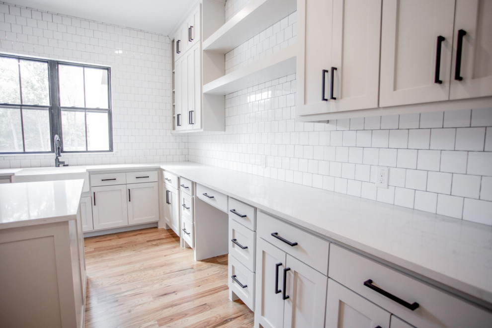 Photo of a large country u-shaped dedicated laundry room in Dallas with a farmhouse sink, shaker cabinets, white cabinets, quartzite benchtops, white walls, light hardwood floors, a side-by-side washer and dryer, beige floor and white benchtop.