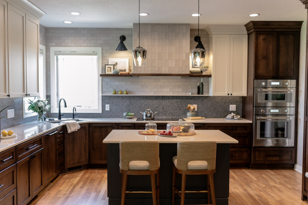 Mid-sized transitional l-shaped medium tone wood floor and brown floor eat-in kitchen photo with an undermount sink, recessed-panel cabinets, dark wood cabinets, quartz countertops, blue backsplash, mosaic tile backsplash, stainless steel appliances, an island and white countertops