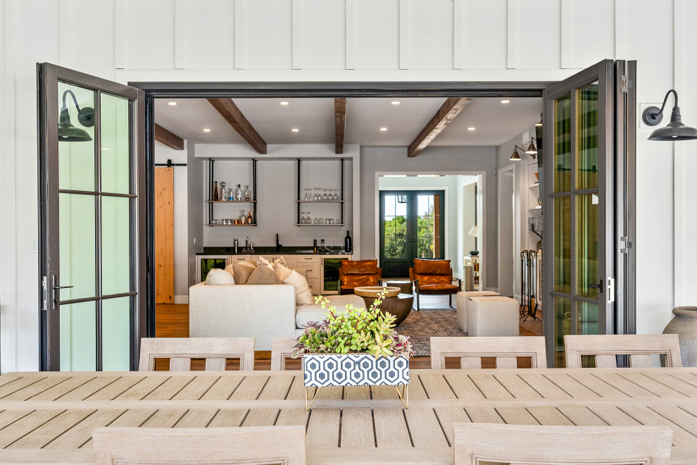 Aménagement d'une très grande terrasse arrière campagne avec une cuisine d'été, des pavés en béton et une extension de toiture.