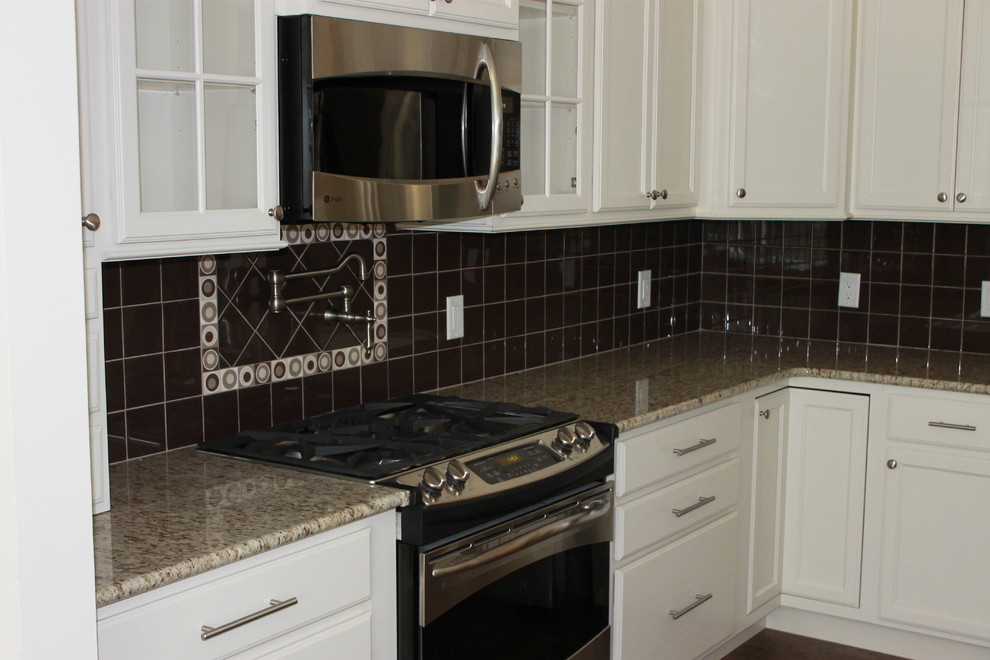 Eat-in kitchen - mid-sized transitional u-shaped dark wood floor eat-in kitchen idea with white cabinets, granite countertops, black backsplash, ceramic backsplash, stainless steel appliances, an island, a double-bowl sink and shaker cabinets