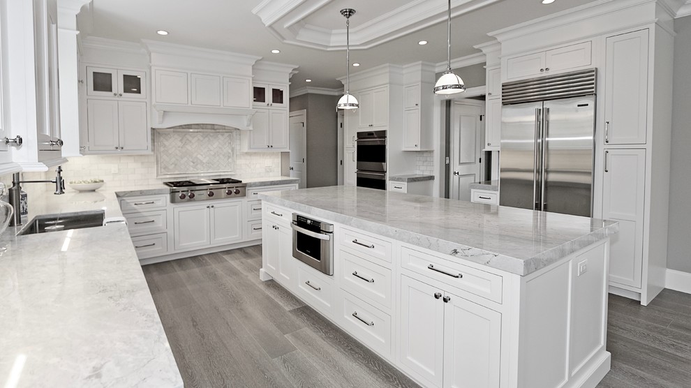 Mid-sized transitional u-shaped eat-in kitchen in New York with an undermount sink, flat-panel cabinets, white cabinets, granite benchtops, subway tile splashback, stainless steel appliances, medium hardwood floors, with island, grey floor and grey benchtop.