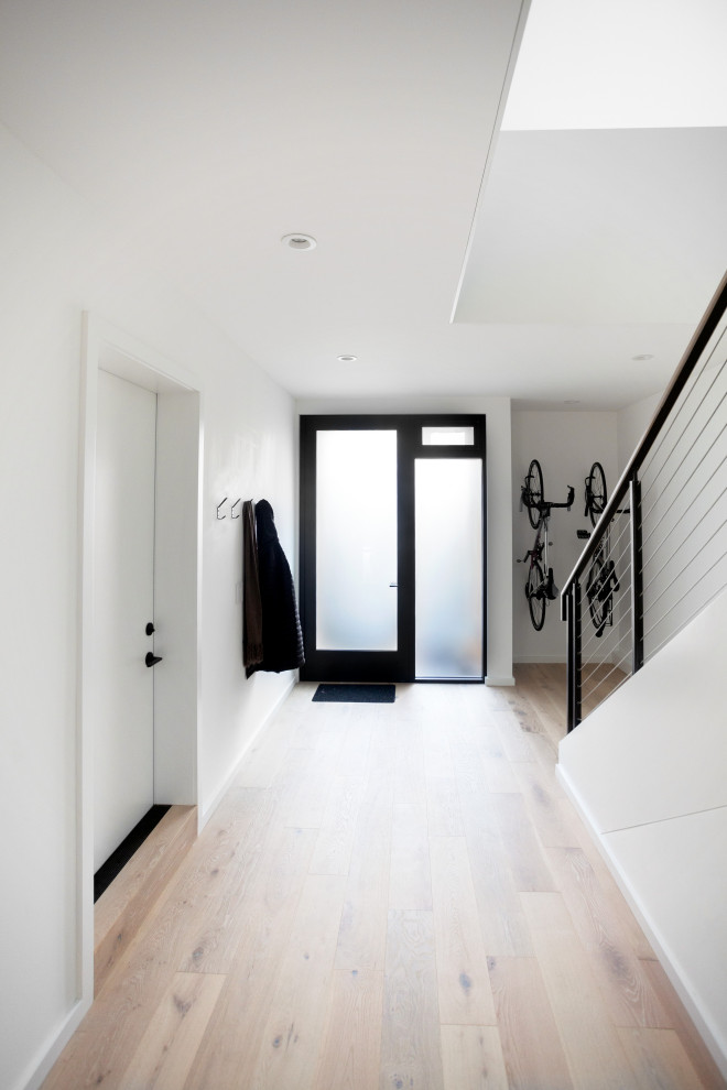 Idée de décoration pour une porte d'entrée minimaliste de taille moyenne avec un mur blanc, parquet clair, une porte simple et une porte métallisée.
