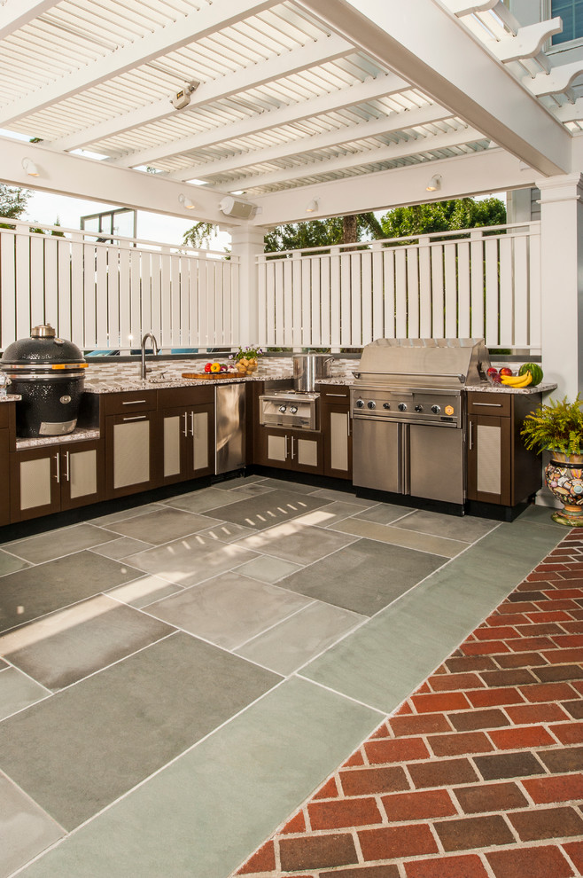 Photo of a large contemporary backyard patio in New York with an outdoor kitchen, brick pavers and an awning.