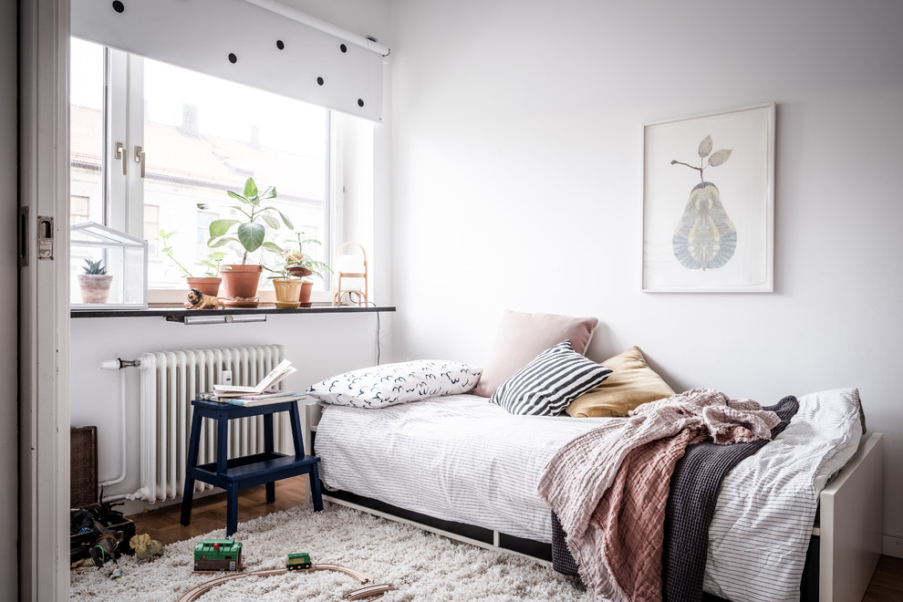 Scandinavian gender-neutral kids' bedroom in Gothenburg with white walls, medium hardwood floors and brown floor for kids 4-10 years old.