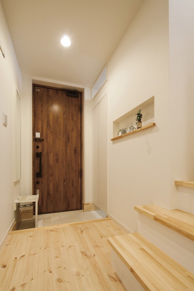 Design ideas for a scandinavian entry hall in Other with brown walls, light hardwood floors, a single front door, a dark wood front door and beige floor.