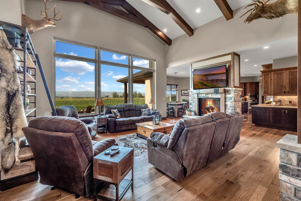 Mid-sized country open concept living room in Denver with beige walls, medium hardwood floors, a two-sided fireplace, a stone fireplace surround and multi-coloured floor.