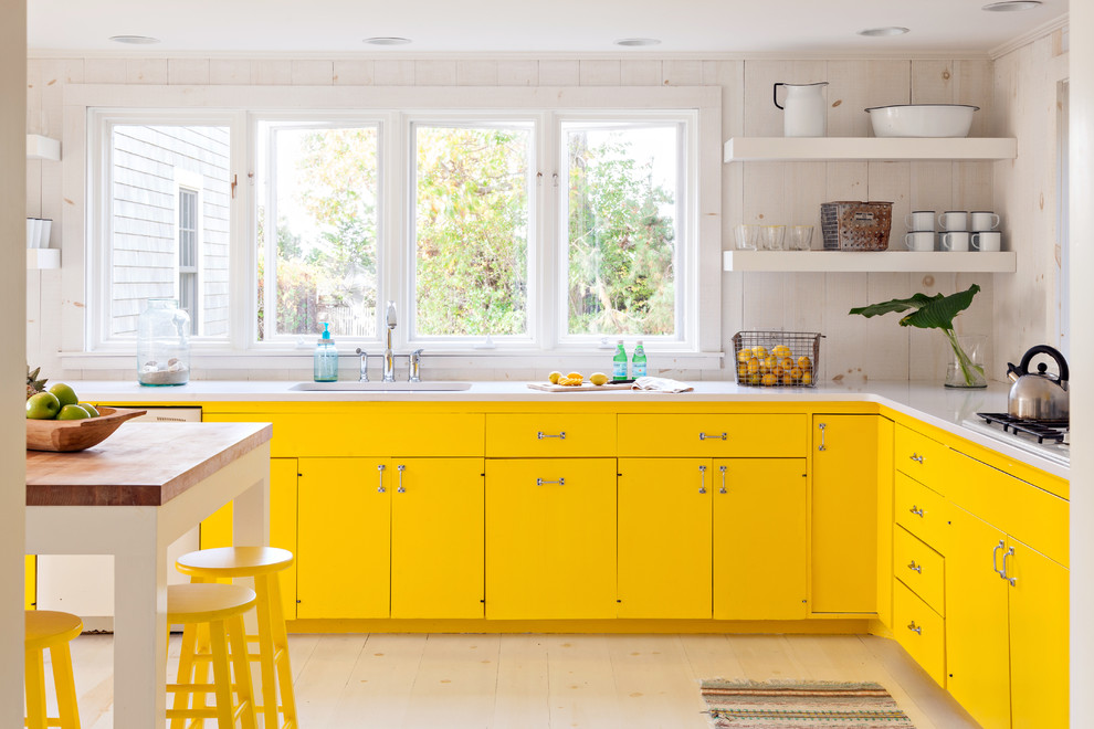 This is an example of a beach style l-shaped kitchen in Boston with flat-panel cabinets and yellow cabinets.