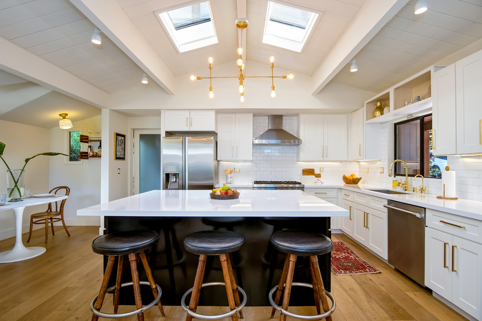 Eat-in kitchen - large transitional light wood floor eat-in kitchen idea in San Diego with an undermount sink, shaker cabinets, white cabinets, white backsplash, subway tile backsplash, stainless steel appliances and an island