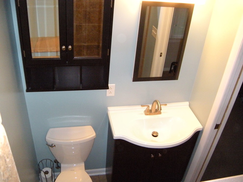 This is an example of a small transitional powder room in Chicago with furniture-like cabinets, black cabinets, a two-piece toilet, blue walls, porcelain floors, an integrated sink and beige floor.