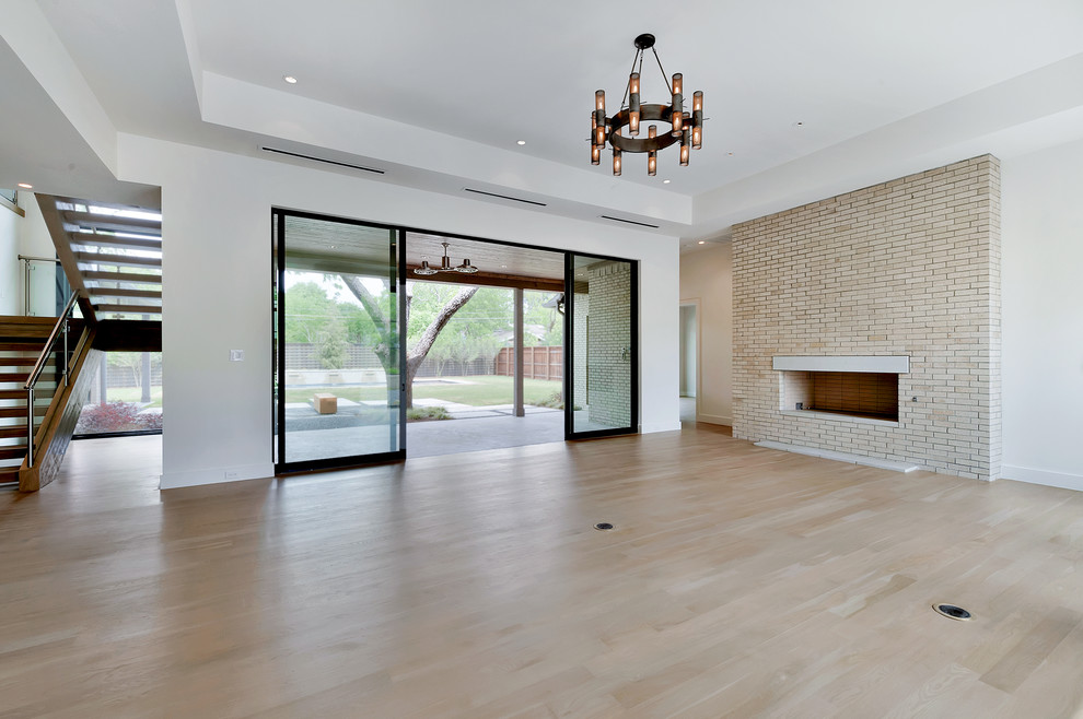 Large modern open concept living room in Dallas with white walls, light hardwood floors, a standard fireplace and a brick fireplace surround.
