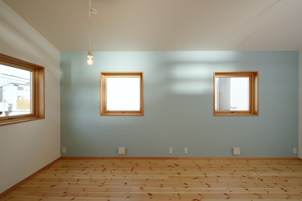 Cette image montre une chambre d'enfant minimaliste avec un mur bleu, parquet clair, un plafond en papier peint et du papier peint.