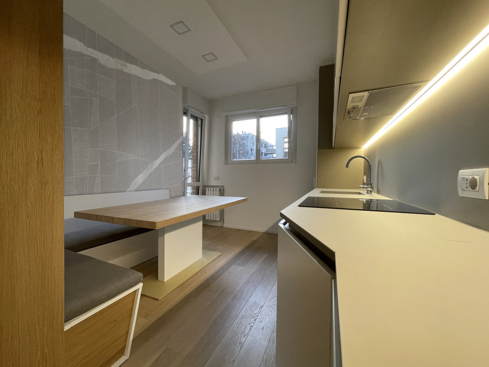 Bild på ett mellanstort funkis grå linjärt grått kök med öppen planlösning, med en enkel diskho, släta luckor, vita skåp, kaklad bänkskiva, grått stänkskydd, svarta vitvaror, mellanmörkt trägolv och brunt golv