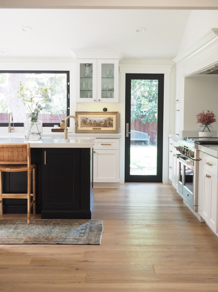 Large traditional u-shaped kitchen/diner in San Francisco with a belfast sink, shaker cabinets, white cabinets, quartz worktops, stainless steel appliances, medium hardwood flooring, an island, brown floors, white worktops and a vaulted ceiling.