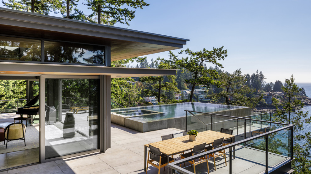 Photo of an expansive modern rooftop rectangular infinity pool in Vancouver with with a pool and concrete pavers.