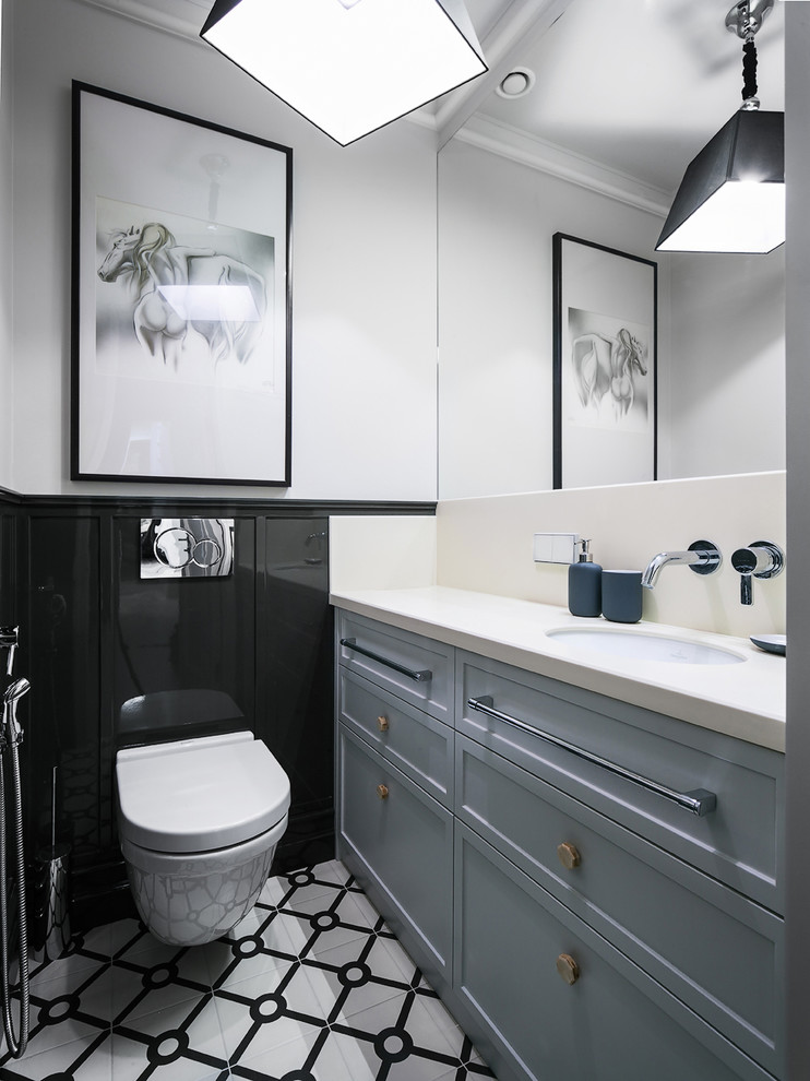 Photo of an eclectic powder room in Saint Petersburg with recessed-panel cabinets, grey cabinets, a wall-mount toilet, black and white tile, black tile, white walls, an undermount sink and multi-coloured floor.